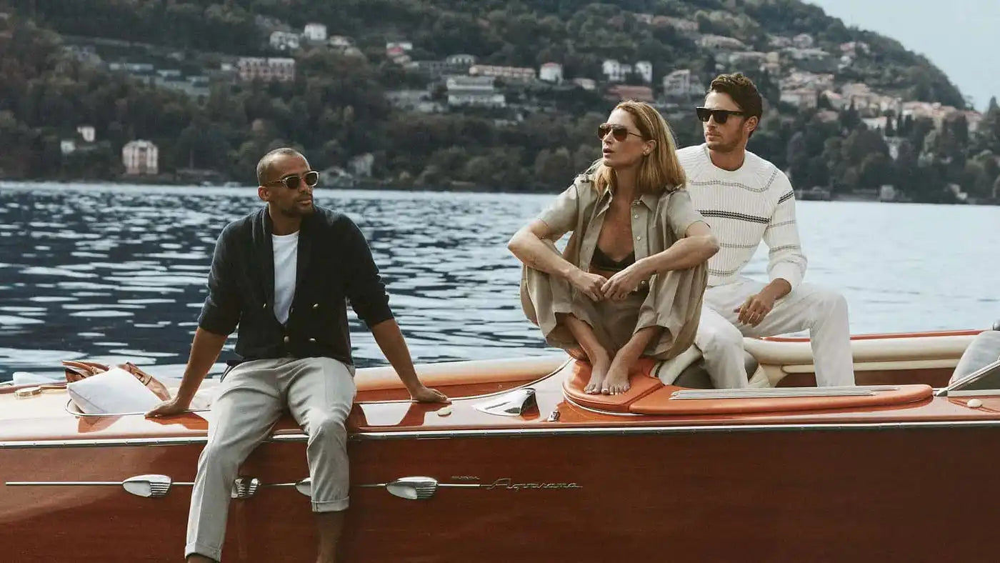 Three people on a classic wooden motorboat.