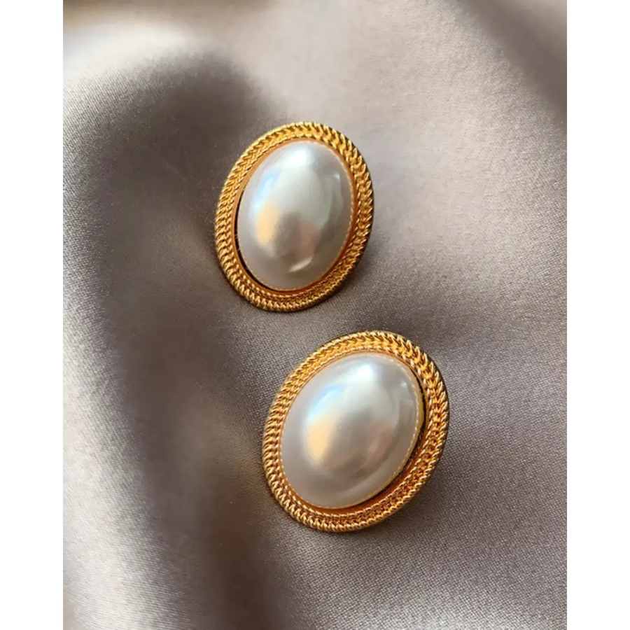 Gold oval pearl studs displayed in velvet pouch, pair view