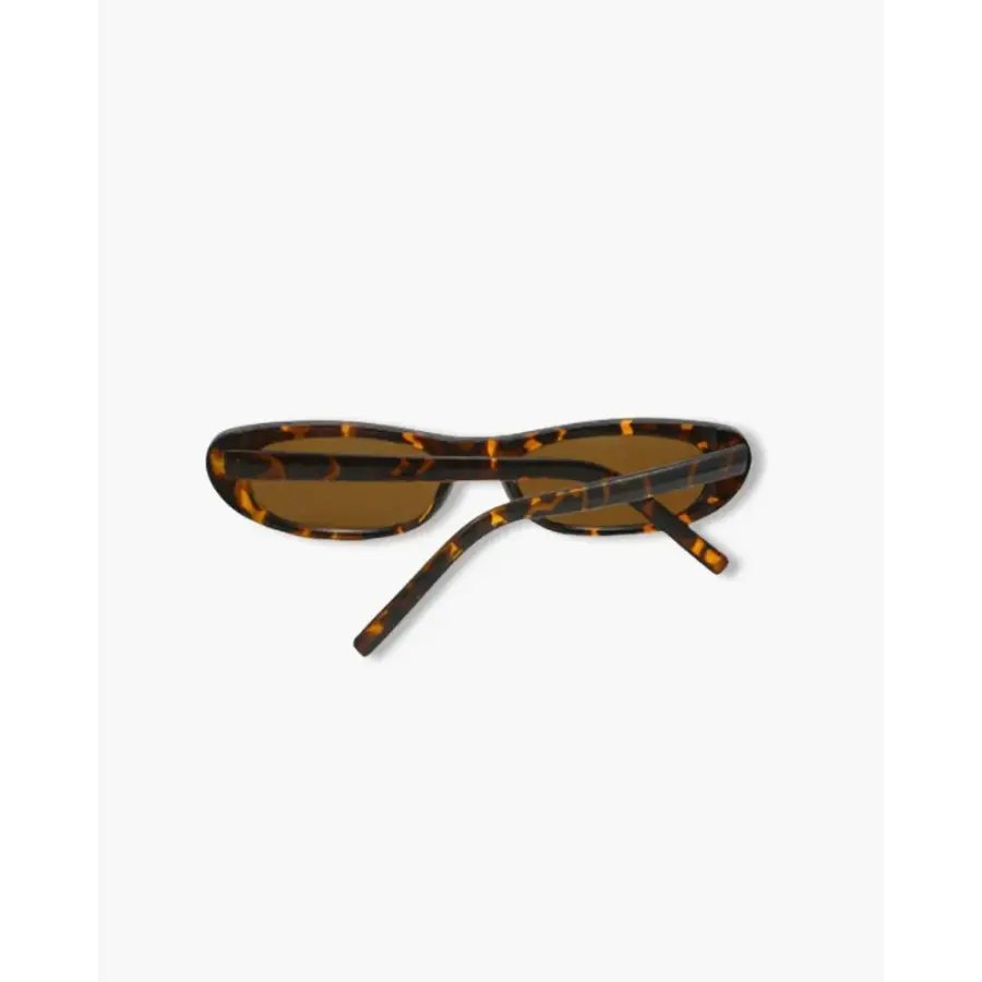 Leopard oval frame sunglasses styled with resort wear, natural setting